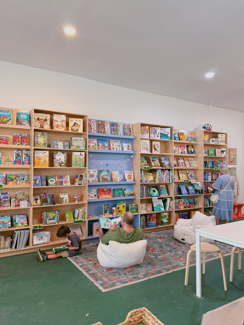 A child reading on the rug beside the bookshelves at Tyrannosaurus Tot